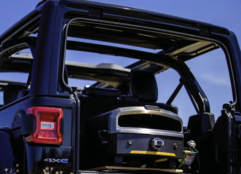 Halo Versa 16 portable propane pizza oven packed in a vehicle for tailgating with a 1 lb cylinder connected