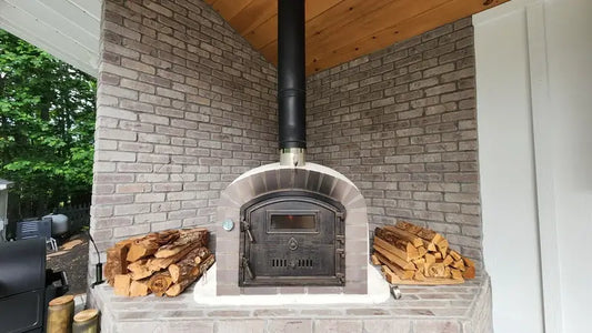 Authentic Pizza Ovens Lume Alto brick oven on a covered porch with the black flue run up through the wood ceiling and brick walls on three sides