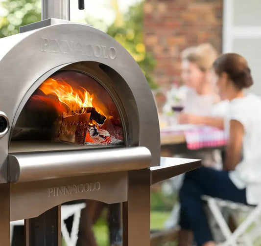 Pinnacolo PREMIO wood fired pizza oven burning a live fire at a backyard dinner, the hero best wood fired pizza oven pick