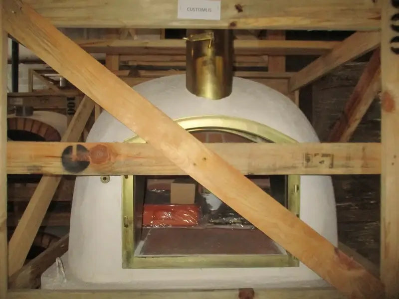 Builders custom Lisboa dome from Authentic Pizza Ovens as it arrives, bare white dome in its wooden crate with the chimney spout fitted and the arched door frame exposed