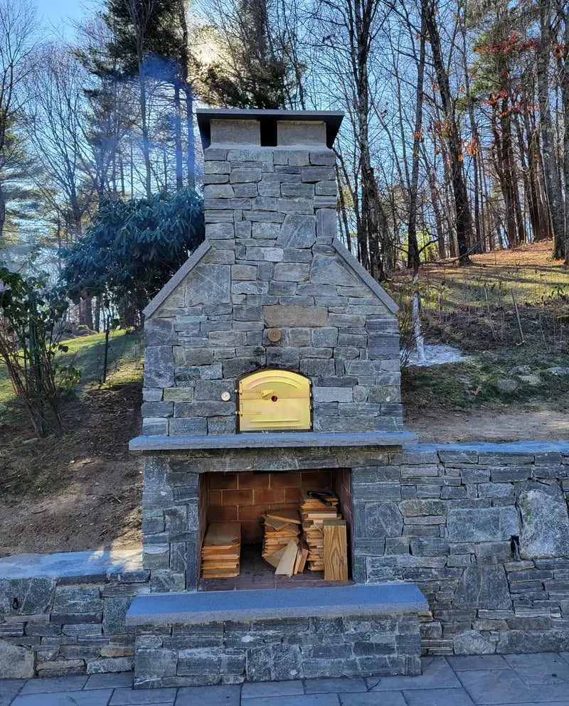 The same builders custom Lisboa dome finished by its owner in fieldstone with a full stone chimney, brass door, thermometer, and a wood store in the base