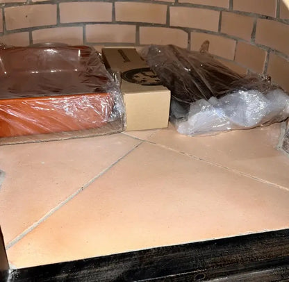Inside the builders custom Pizzaioli dome, the fire brick walls and tile floor with the included ceramic dish and thermometer box packed on the floor