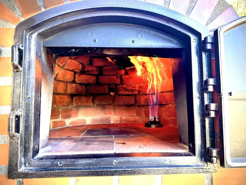 Vamparossa gas burner lit inside an Authentic Pizza Ovens hybrid ready brick oven, seen through the open door