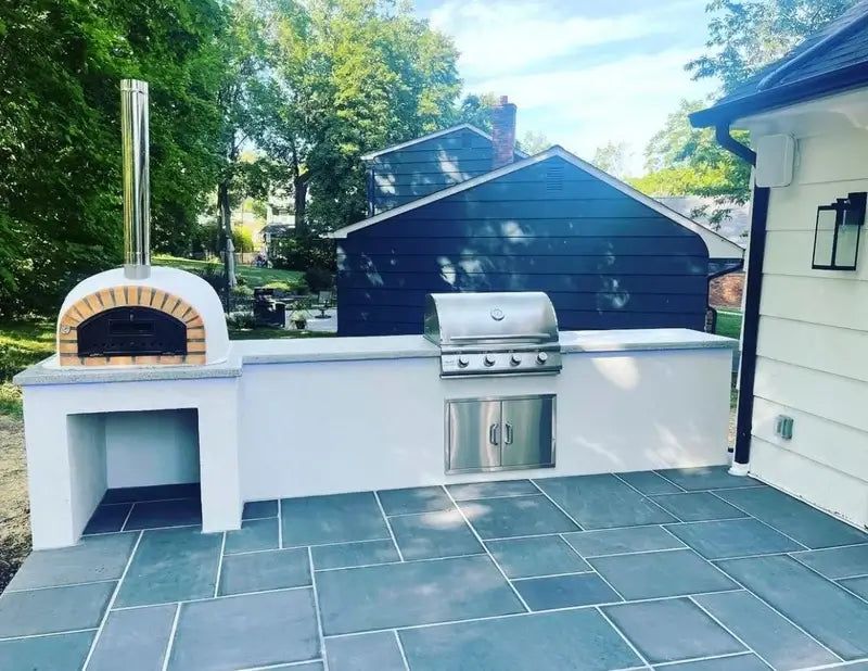 Pizzaioli Premium built into a white outdoor kitchen counter beside a gas grill