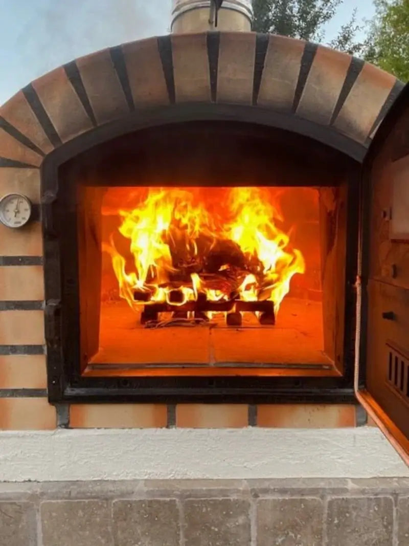 Wood fire burning on the brick floor of an Authentic Pizza Ovens brick oven, seen through the open door
