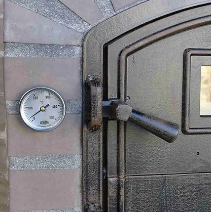 Close up of the dial thermometer set in the cast stone beside the Lume Alto Tudo door latch and viewing window