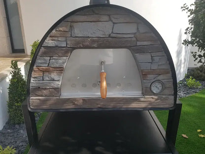 Maximus Mobile pizza oven in Black straight on, gray stacked stone front around the stainless door with air holes and the dial thermometer at the right