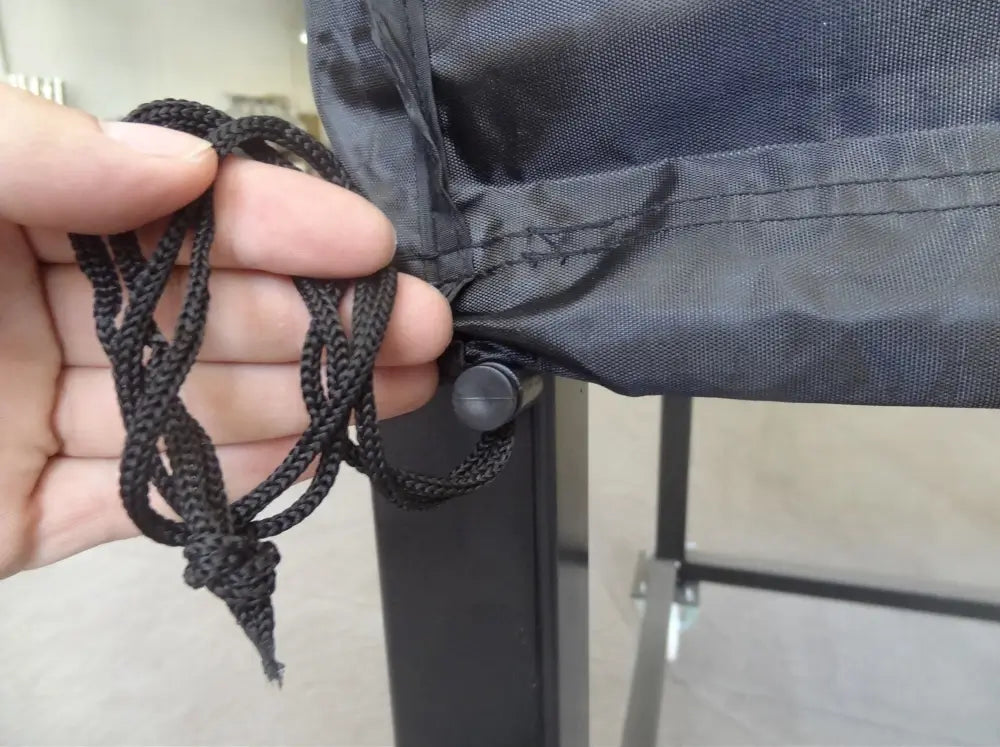 Close up of the drawstring and cord lock at the hem of the Maximus Mobile pizza oven cover being cinched under the oven