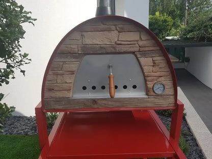 Maximus Mobile pizza oven in Red straight on, sand toned stacked stone front around the stainless door with air holes and the dial thermometer at the right, on the red APO stand