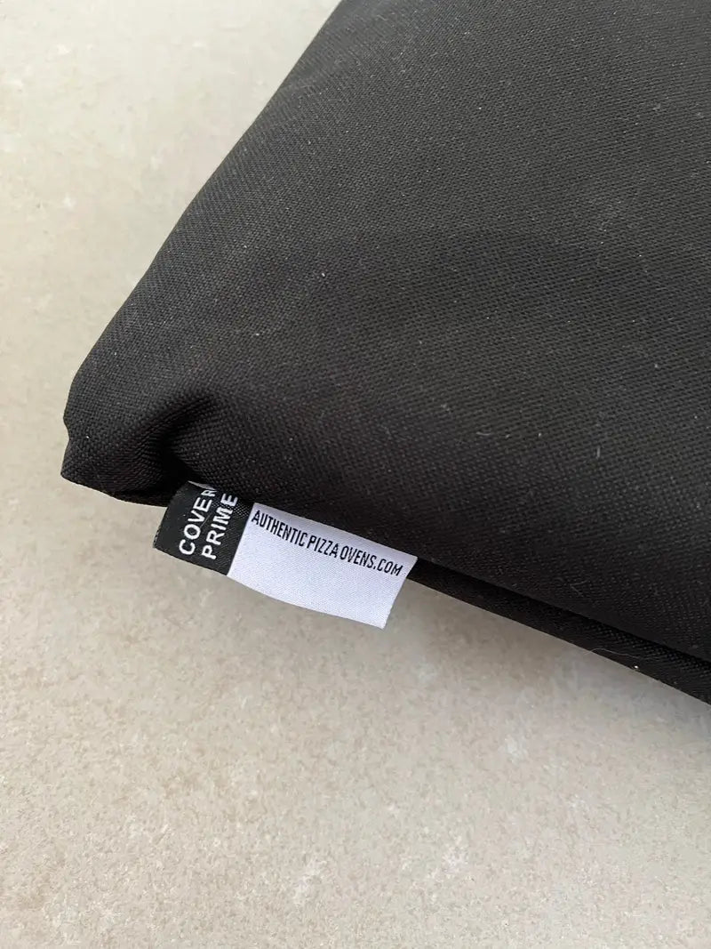 Folded Maximus Prime pizza oven cover showing the woven Cover Prime label and the Authentic Pizza Ovens tag