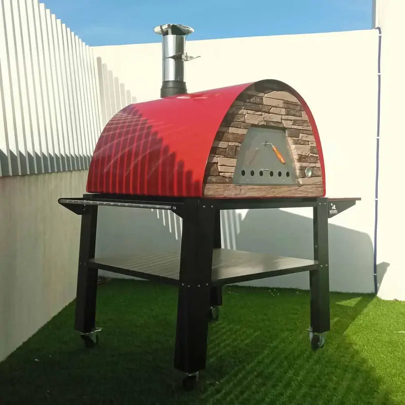 Red Maximus Prime on the Authentic Pizza Ovens Bello stand, side view on artificial grass showing the black steel frame, lower shelf, and casters