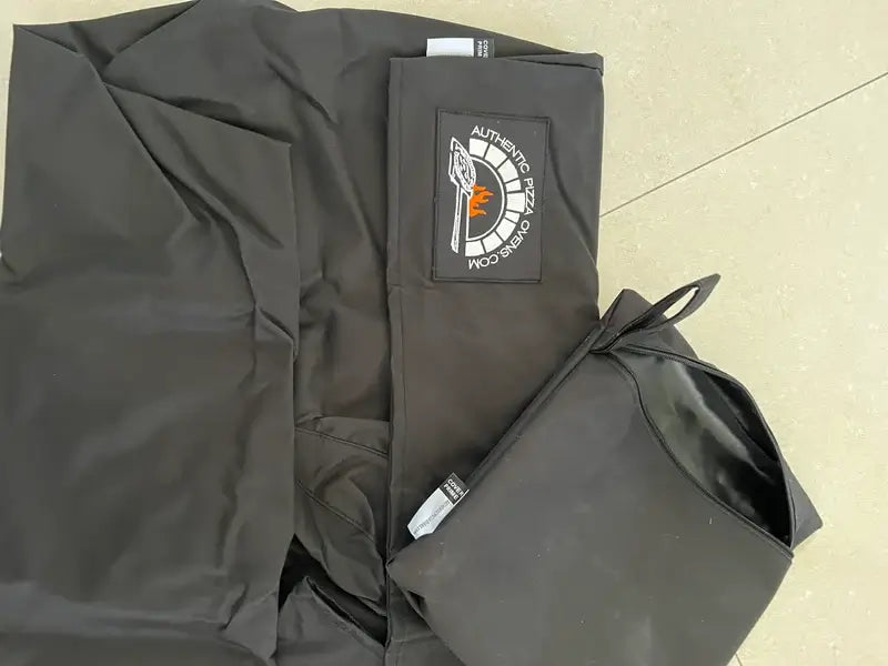 Authentic Pizza Ovens oven cover laid flat showing the embroidered brand patch and the zippered storage bag