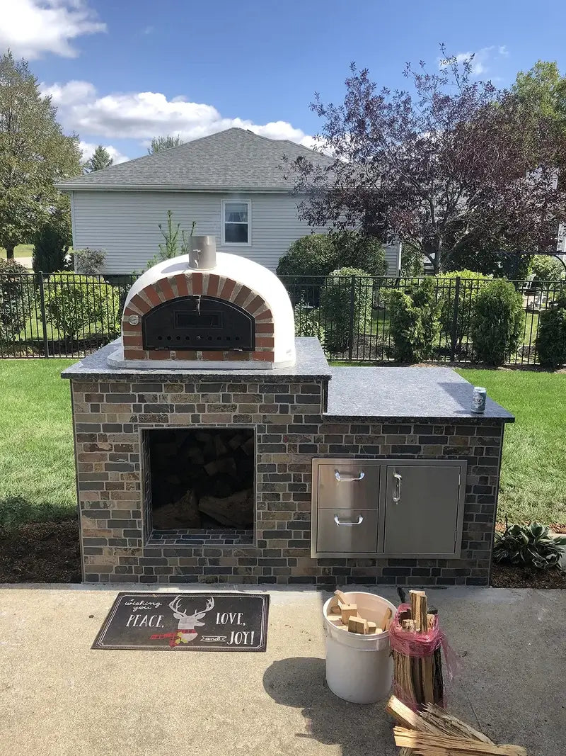 Pizzaioli Rustic Arch installed on a stone veneer outdoor kitchen with granite counter, wood storage, and stainless doors