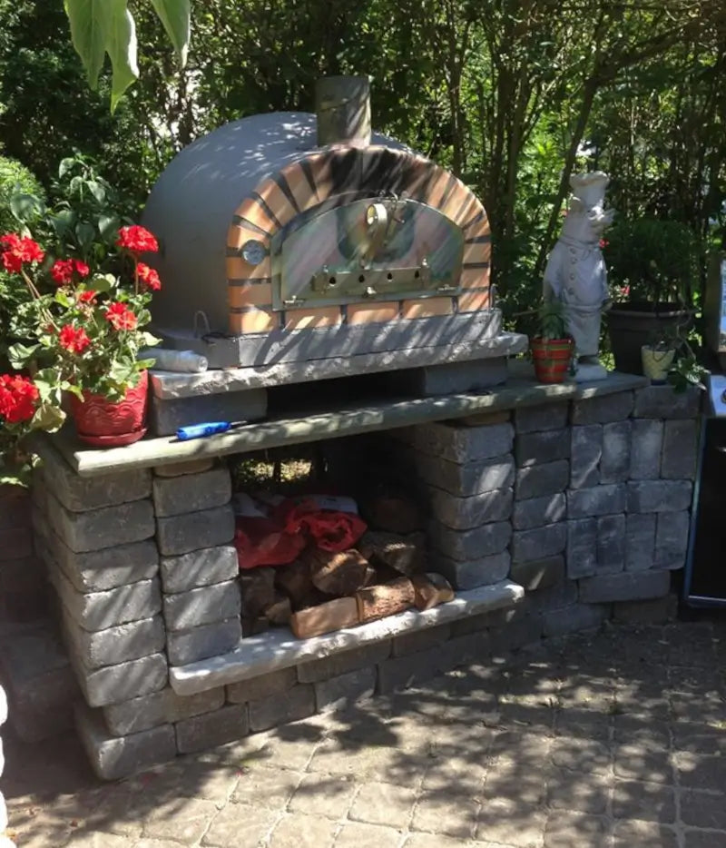 Authentic Pizza Ovens Pizzaioli Standard with iron door installed on a stacked concrete block base with wood storage in a garden