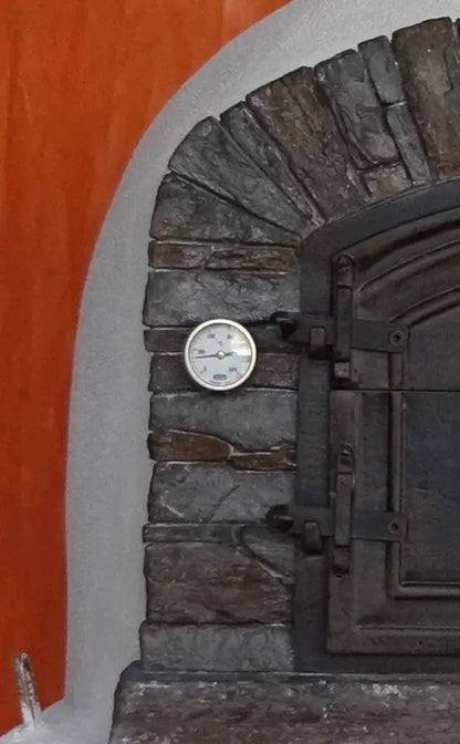 Close up of the dial thermometer fitted into the stacked stone facade beside the door of a Ventura Preto pizza oven