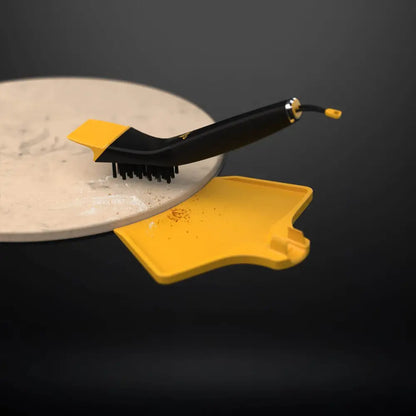 Halo Pizza Stone Cleaning Kit brush sweeping a cooled pizza stone with the ash pan catching debris at the edge