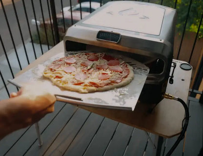 Launching a pepperoni pizza into the Halo Versa 16 pizza oven on a balcony