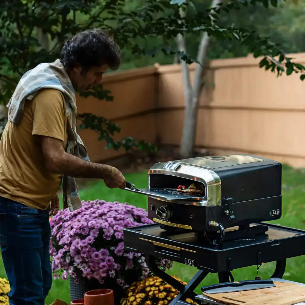 Cooking pizza on a Halo Versa 16 pizza oven mounted on the Halo Countertop Cart in a backyard