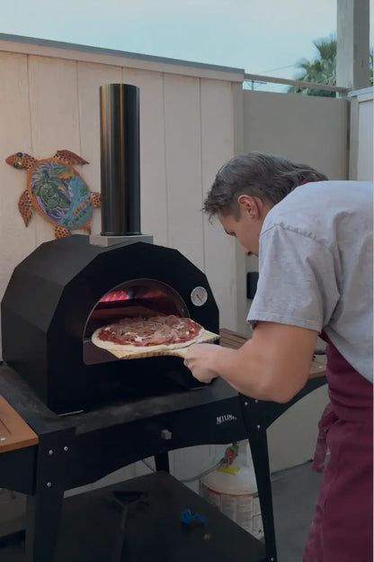 Pizza going into the ItaliaForno Bambino on a stand with the propane tank on the shelf below