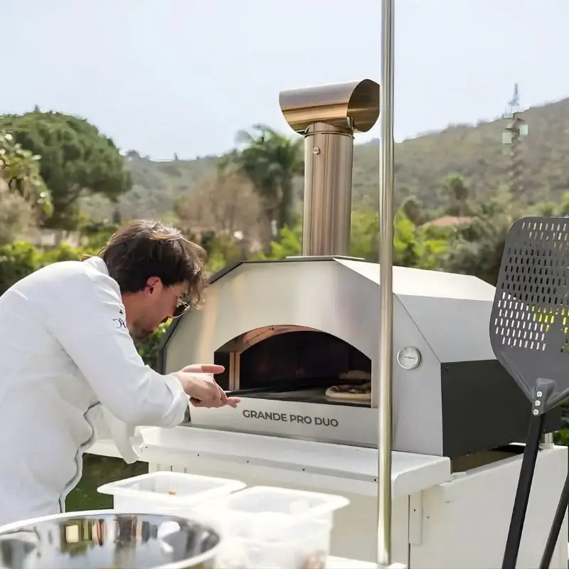 Cook launching a pizza into the ItaliaForno Grande Pro Duo outdoors